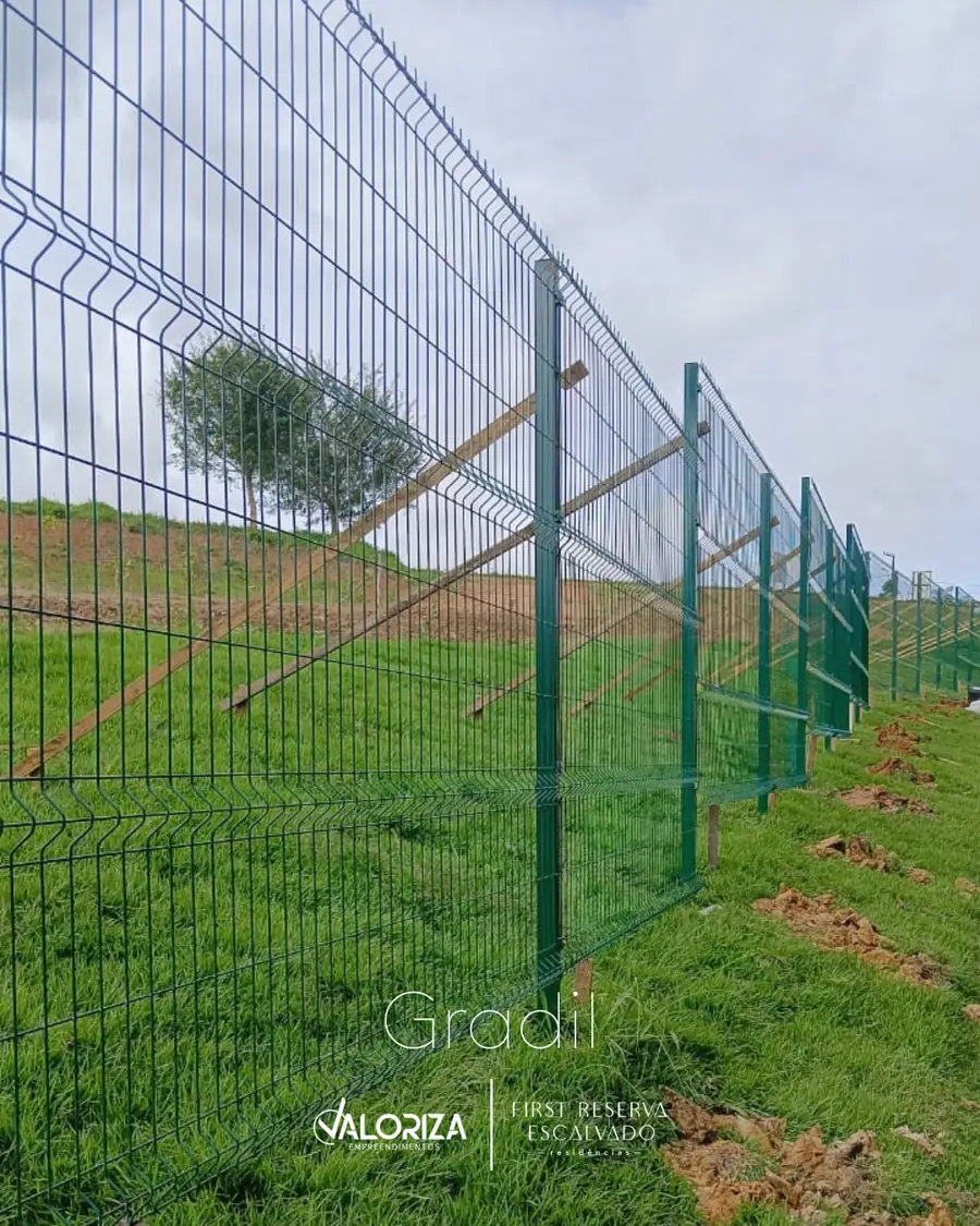 Gradil verde montado sobre o talude gramado, acompanhando a divisa
