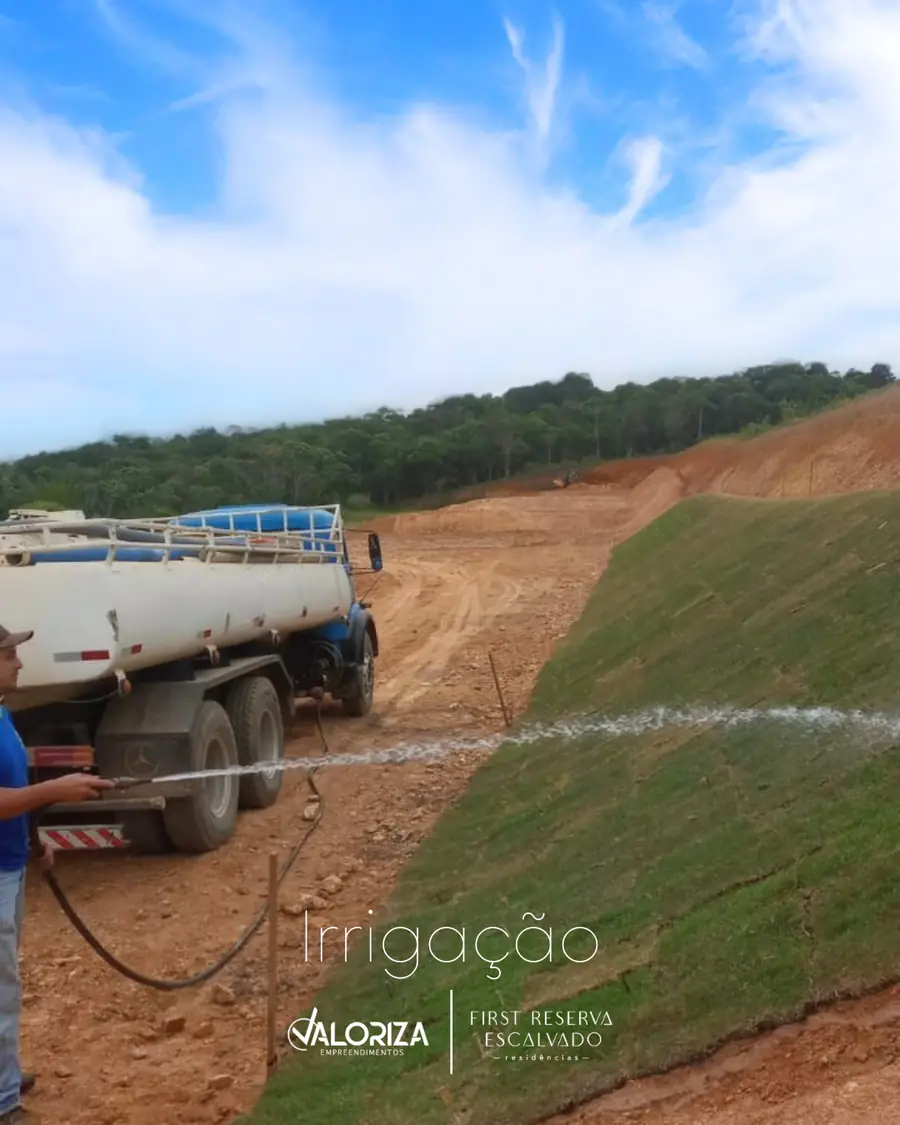 Caminhão-pipa irrigando o talude gramado ao lado da via de acesso