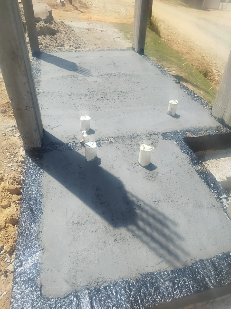 Base de concreto recém-executada, com os chumbadores dos pilares aparentes